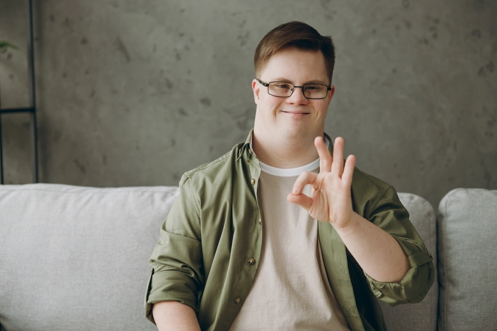down syndrome disability boy sitting on sofa and posing for camera