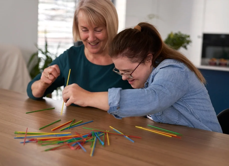 instructor helping young women with down syndrome disability in learning and identifying colors