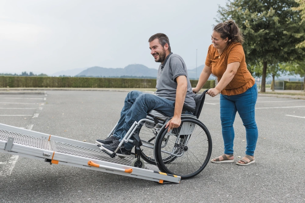 women pushing disabled man on wheelchair on van