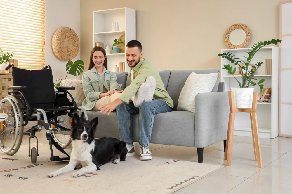 Young couple with disabled wife sitting on sofa with a pet dog